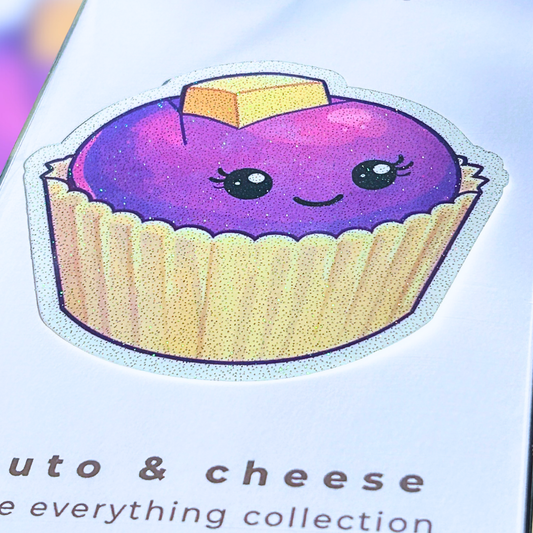close up image of a card with a purple ube puto and cheese die cut decal held by a hand against a colorful background