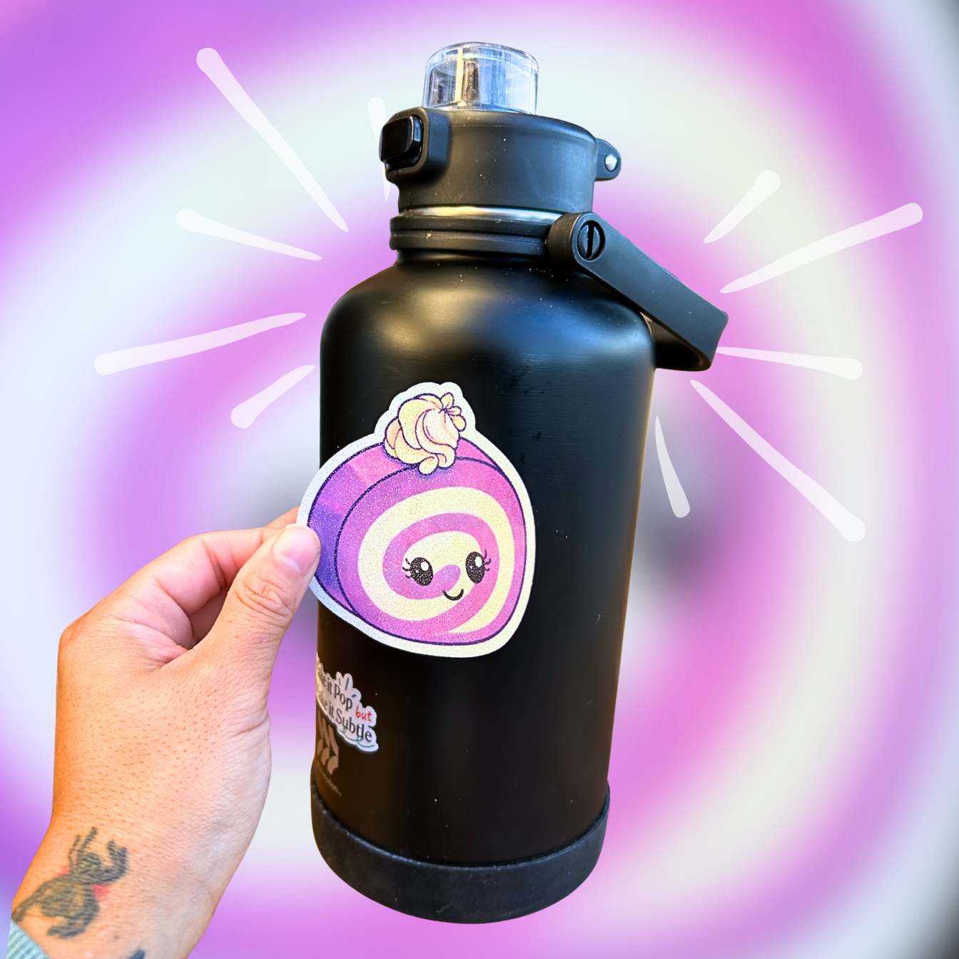 Image of a hand placing an extra large die-cut ube roll cake sticker onto a large black water bottle.