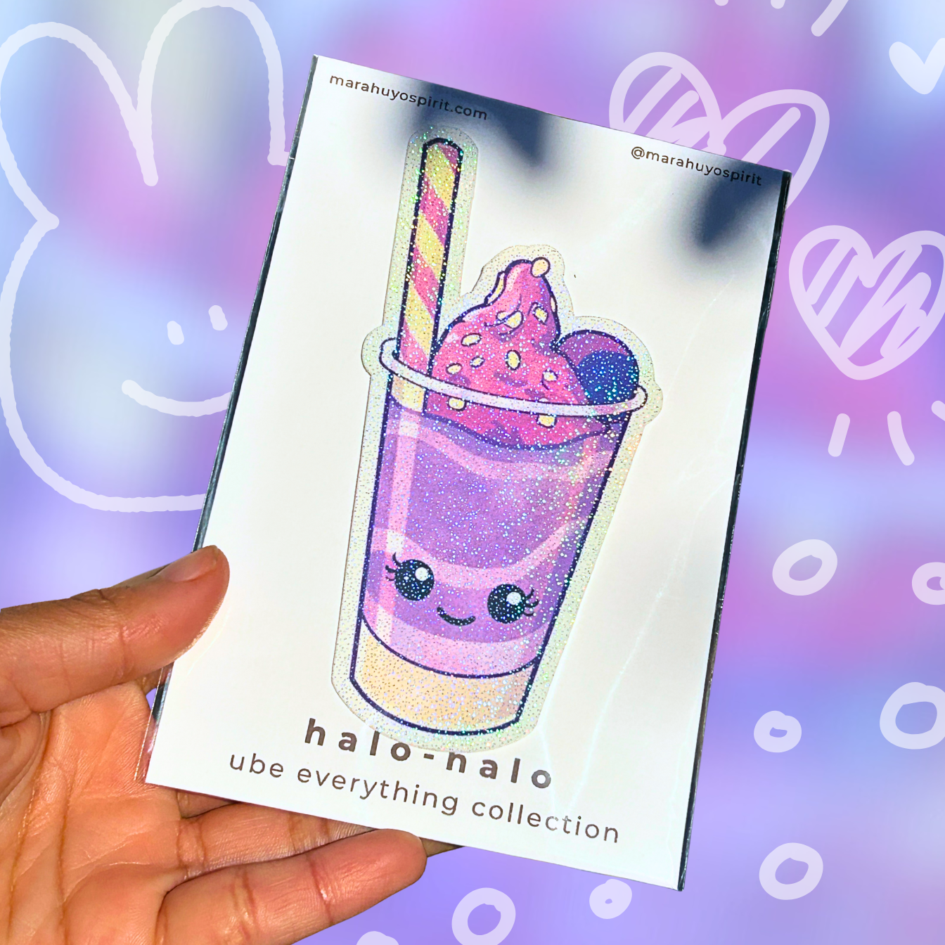 Hand holding a card with a cute ube halo-halo glitter die-cut decal and 'halo-halo' branding on a colorful background.